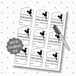 May include: A sheet of nine rectangular gift tags with pointed tops, featuring black text that reads You've been PIXIE DUSTED Have a Magical day! FROM: and a black silhouette of a mouse-ear key icon with small purple star accents, plus a black pen.