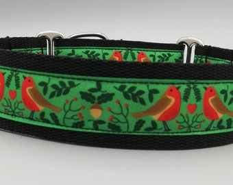 Könnte beinhalten: Ein schwarzes Hundehalsband mit einem grünen und roten Rotkehlchenmuster. Das Halsband hat eine schwarze Basis mit einem grünen Band, das mit roten Rotkehlchen, Eicheln und Blättern verziert ist. Das Halsband hat Metallbeschläge.