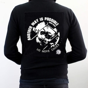 May include: Black zip-up hoodie with a white graphic on the back that says "Another Way Is Possible Choose Vegan" and "No More Cages".