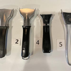 May include: A white ceramic mug with a black handle and the text "But First, Coffee" in a bold, black font. The mug is set against a blurred background, suggesting a cozy setting.