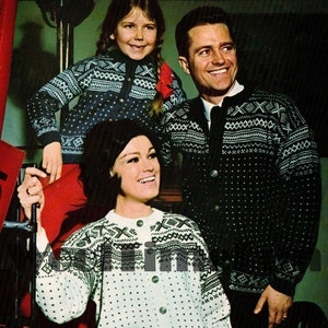 May include: A family wearing traditional Norwegian jumpers with a black and white geometric pattern. The jumpers have a button-up front and are made of a soft, warm material. The jumpers are a classic style that is perfect for the winter months.