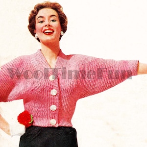 May include: A pink knitted cardigan with a V-neck and button fastening. The cardigan has a short, cropped style and long sleeves.