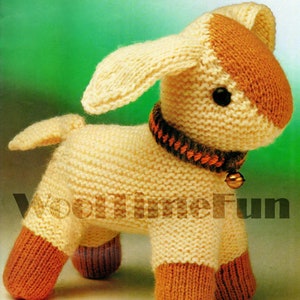 May include: A knitted lamb toy in cream and brown. The lamb has a brown head, ears, and feet. It wears a black and orange collar with a small gold bell. The text "Wooltimefun" is visible on the lower left side of the image.