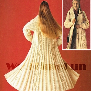 May include: A long, white knitted coat with a cable knit pattern. The coat has a high collar and a button closure. The model is wearing the coat with brown boots.