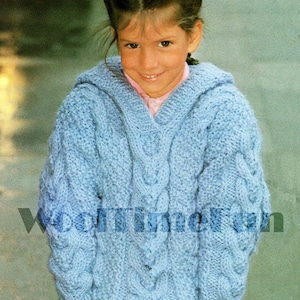 May include: A light blue knitted jumper with a cable knit pattern. The jumper has a v-neck and a hood. The jumper is worn by a young girl with her hair in pigtails.