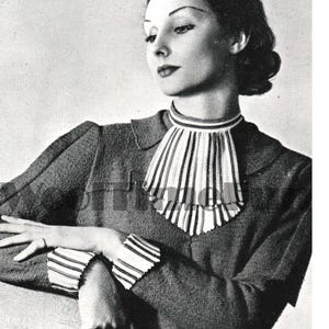 May include: A black and white photo of a woman wearing a collared jacket with a pleated white and black collar. The jacket has striped cuffs. The woman is holding a black handbag.