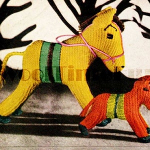 May include: Two knitted stuffed animals, a yellow horse and an orange donkey, are posed against a black background. The horse has a pink bridle and green and brown stripes. The donkey has green and yellow stripes.