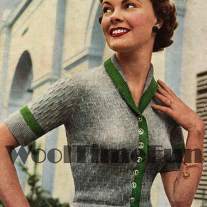 May include: A gray knitted cardigan with green trim and button closures. The cardigan has short sleeves and a fitted waist.
