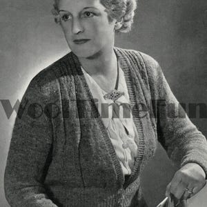 Könnte beinhalten: Eine Frau trägt einen grauen Strickcardigan mit V-Ausschnitt und einer dekorativen Brosche. Sie hält eine Zeitschrift in ihren Händen.