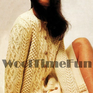 Puede incluir: Un cárdigan de punto de color crema con un patrón de trenza y cierre de botones. El cárdigan lo lleva una modelo con el pelo largo y oscuro.