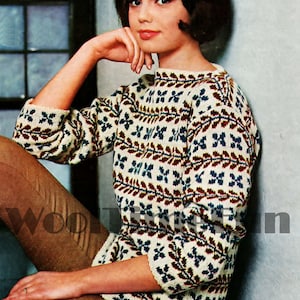 May include: A woman wearing a white, blue, brown, and red patterned sweater with a crew neck. The sweater has a geometric design.
