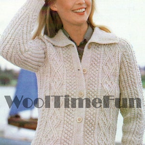 May include: A cream-colored knitted cardigan with a cable knit pattern and button closure. The cardigan has a collar and long sleeves. The model is wearing a plaid skirt.