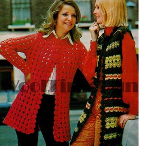 May include: Two women wearing crocheted garments. One woman is wearing a red crocheted cardigan with a scalloped hem. The other woman is wearing a green, yellow, and red striped crocheted scarf.