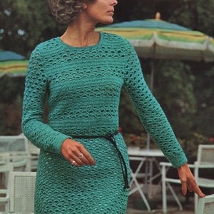 May include: A teal crochet dress with long sleeves and a belt. The dress has a lacy pattern and is shown on a model with curly hair. The text "Crochet dress" and "3 sizes: 33-38 (84-96 cm)" is visible in the image.