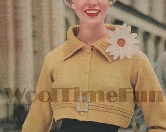 Pode incluir: Uma mulher vestindo um casaco de tricô amarelo curto com um broche de margarida branca, uma saia preta e um chapéu branco. O casaco tem fecho de botão e cinto. O texto "WoolTimeFun" é visível na imagem.