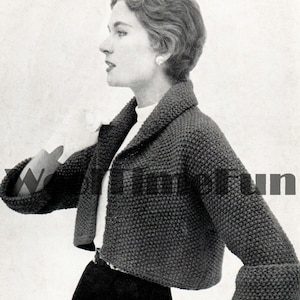 Könnte beinhalten: Nahaufnahme einer Frau, die einen dunkelgrauen, gekürzten Strickcardigan mit Kragen trägt. Der Cardigan hat ein strukturiertes Strickmuster und wird über einem weißen Hemd getragen.