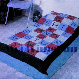 May include: A blue and white alphabet blanket with red squares. The blanket is made of knitted yarn and features the letters of the alphabet in a checkered pattern.