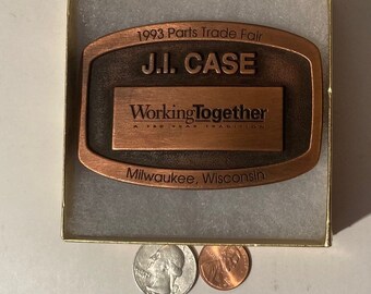 Puede incluir: Una hebilla de cinturón de color cobre con el texto "1993 Parts Trade Fair J.I. CASE Working Together A NEW WAY TO TRANSITION Milwaukee, Wisconsin".