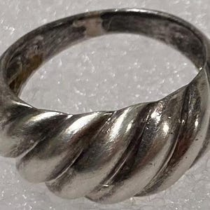 May include: A silver ring with a twisted, rope-like design. The ring is smooth and polished.