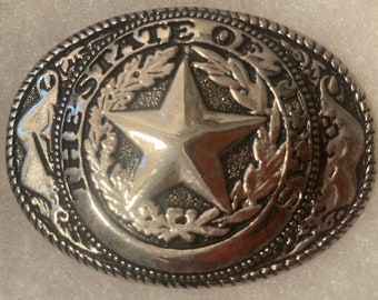 May include: Silver belt buckle with a five-pointed star surrounded by a wreath and the text "THE STATE OF TEXAS".