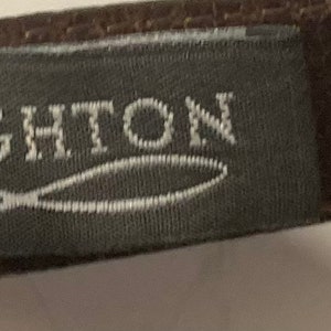 Puede incluir: Un cintur&oacute;n de cuero marr&oacute;n con una etiqueta gris que dice "BRIGHTON" y una etiqueta blanca con el n&uacute;mero "L 4699".