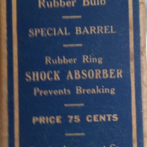 Könnte beinhalten: Ein blaues und weißes Etikett mit dem Text "Fine Rubber Bulb, Special Barrel, Rubber Ring, Shock Absorber, Prevents Breaking, Price 75 Cents, Testrite Instrument Co., New York".