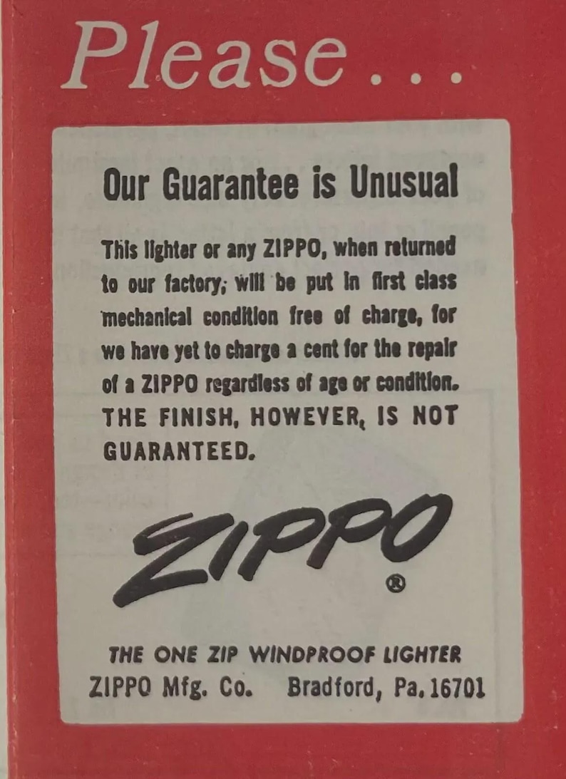 May include: A vintage advertisement for Zippo lighters. The text on the red and white paper reads "Our Guarantee is Unusual" and details the repair policy. The Zippo logo is prominently displayed, along with the company's address in Bradford, PA.