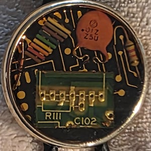 May include: A set of three ceramic mugs with a speckled, matte finish. The mugs are in shades of cream, light gray, and dark gray. Each mug has a simple, minimalist design and a rounded handle. The mugs are likely for coffee or tea.