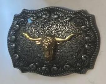 May include: Silver belt buckle with an ornate design and a gold bull's head in the centre.