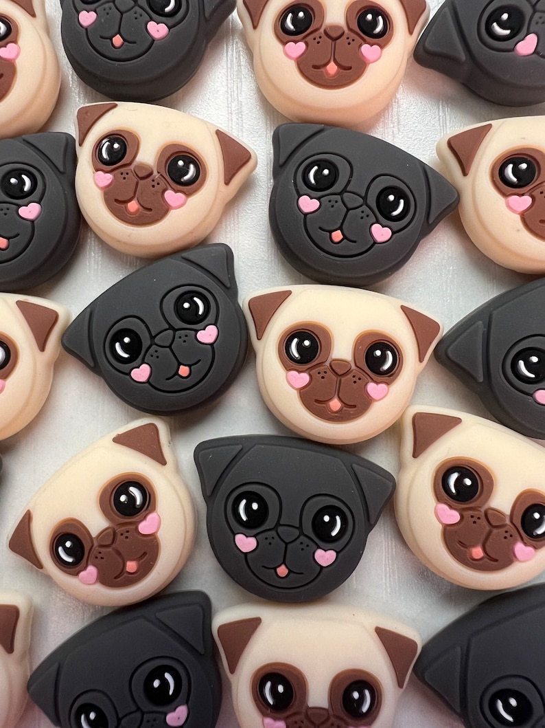 May include: A collection of 16 silicone pug charms in black and beige with pink hearts on their cheeks. The charms are in various poses and expressions.