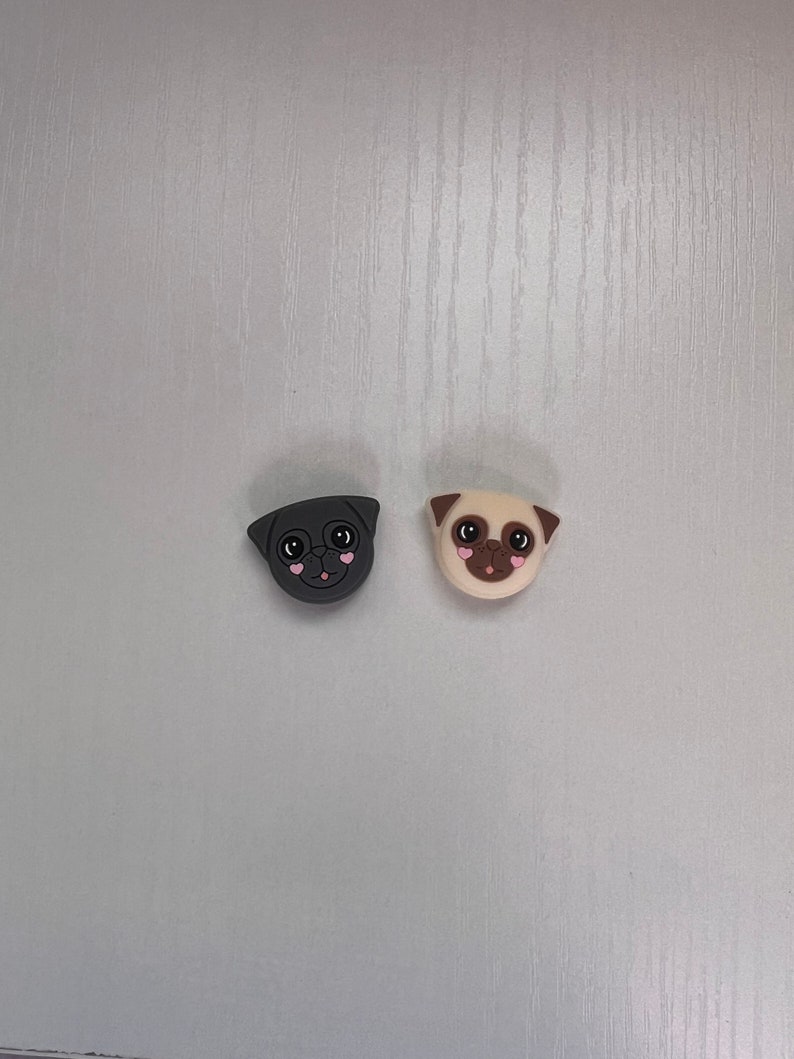 May include: Two pug dog phone charms, one black and one beige, with pink hearts for eyes.