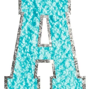 May include: A large letter "A" in a varsity style. The letter is filled with a textured, light blue material. The edges are outlined with silver sequins. The background is white.