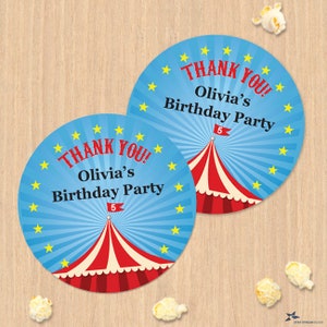 Könnte beinhalten: Zwei runde blaue und weiße Danke-Aufkleber mit einem roten und weißen Zirkuszeltdesign. Der Text auf den Aufklebern lautet "Danke! Olivias Geburtstagsparty 5".