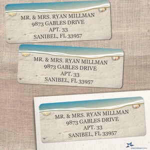 May include: Three white and beige return address labels with a blue and white beach scene at the top. The labels have the text "MR. & MRS. RYAN MILLMAN 9873 GABLES DRIVE APT. 33 SANIBEL, FL 33957" printed on them.