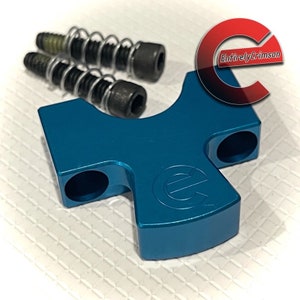 May include: A teal blue metal part with two holes on each side and a logo on the bottom. Two small springs and screws are included.