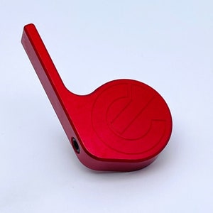 May include: Red metal lever with a rounded end featuring a raised, circular logo with the letter "C" inside.