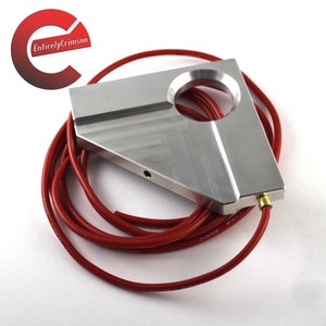 May include: A silver metal triangular shaped object with a large hole in the center and a smaller hole on the side. A red hose is wrapped around the object.