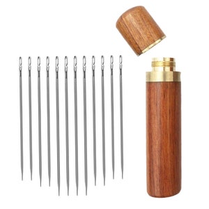 May include: A set of 12 silver sewing needles in a wooden case with a brass top. The case is closed and the needles are visible.