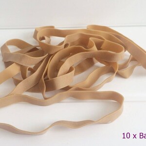 May include: A pile of ten tan elastic bands, shown in a tangled arrangement. These flexible bands are likely for general use. The text "10 x Bands" is displayed in the lower right corner of the image.