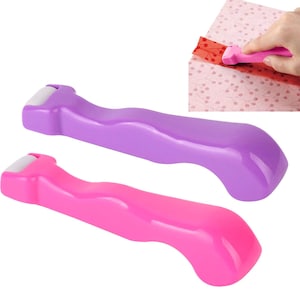 May include: Two plastic tools for wrapping gifts. One is purple and the other is pink. Both have a white roller on the end.