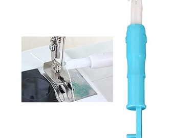 May include: A blue plastic sewing threader tool with a white hook. The tool is used to thread a sewing machine needle.