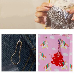 May include: A pink gift bag with a unicorn pattern and a red Christmas tree ornament attached to it. The bag has a white handle and a silver safety pin attached to it.