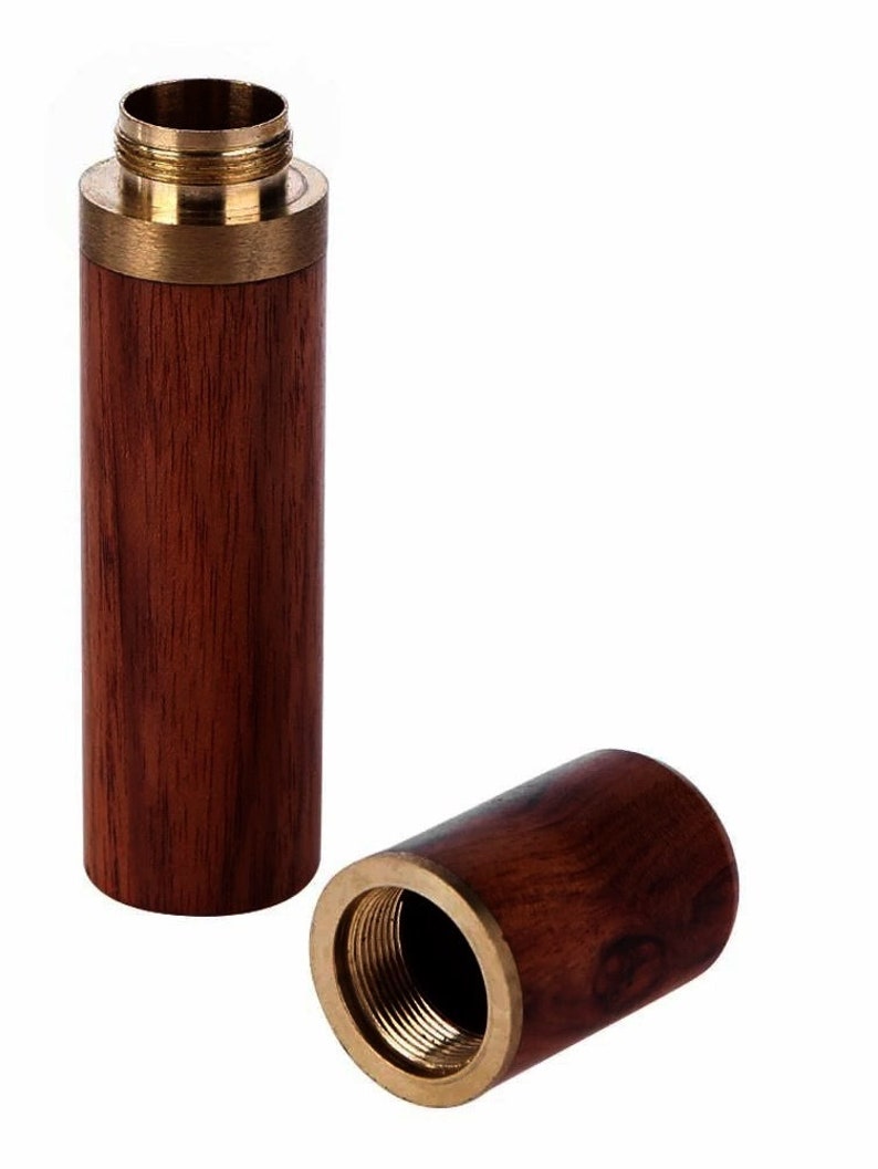 May include: A wooden and brass needle threader. The threader is made of dark wood with a brass top and bottom. The threader is open and the inside is visible.