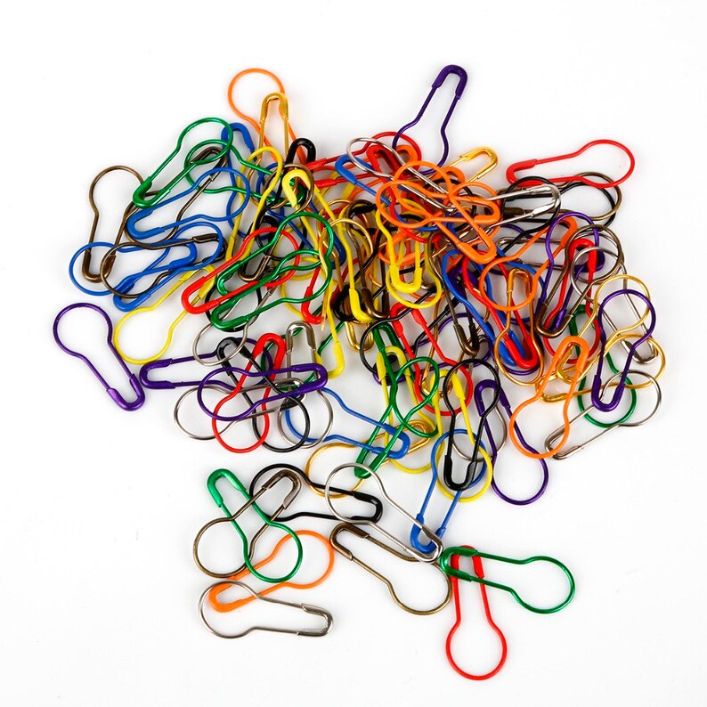May include: A large pile of colorful safety pins in various shades of red, orange, yellow, green, blue, and purple.