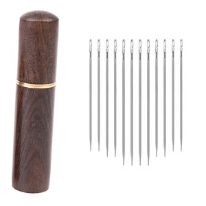 May include: A set of 10 silver sewing needles in a wooden case with a gold band. The case is made of dark brown wood with a wood grain pattern.