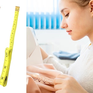 May include: Two yellow measuring tapes with black markings, each measuring up to 25 cm. A person is using a yellow measuring tape to measure fabric while sewing.