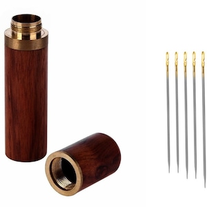 May include: A set of 15 sewing needles in a wooden case. The needles are silver with gold tips. The case is made of dark wood with a brass lid.