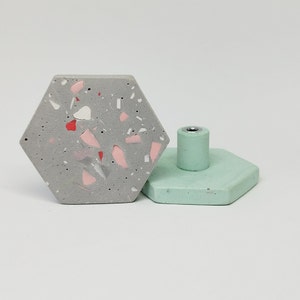 K&ouml;nnte beinhalten: Zwei sechseckige Schrankkn&ouml;pfe. Einer ist grau mit rosa und wei&szlig;en Flecken, der andere ist hellgr&uuml;n. Beide haben eine silberne Schraube in der Mitte.