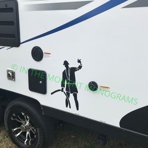 May include: A white camper with a black silhouette of a person holding a hose. The camper has a black trim and a blue stripe. The text "CAUTION" is visible on the camper.