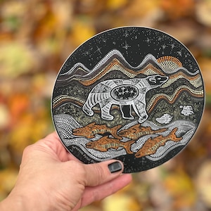 Könnte beinhalten: Ein runder Aufkleber mit schwarzem Hintergrund und einem weißen Eisbären, der auf einer braunen und weißen gemusterten Landschaft steht. Der Bär ist von orangefarbenen und weißen Fischen umgeben. Der Aufkleber trägt den Text "Seventh Petal Design" unten.